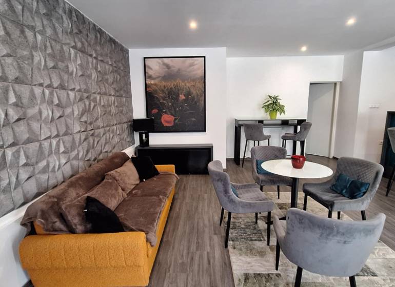 Obývací pokoj v rodinném domě s pohodlnou sedačkou a jídelními židlemi.