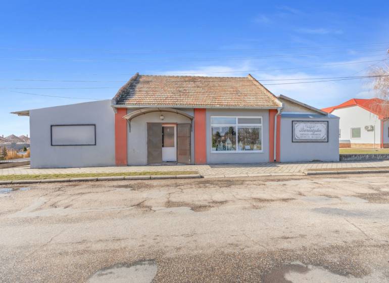 Obchodní prostory ve městě Okoč s výkladními okny a šikmou střechou.