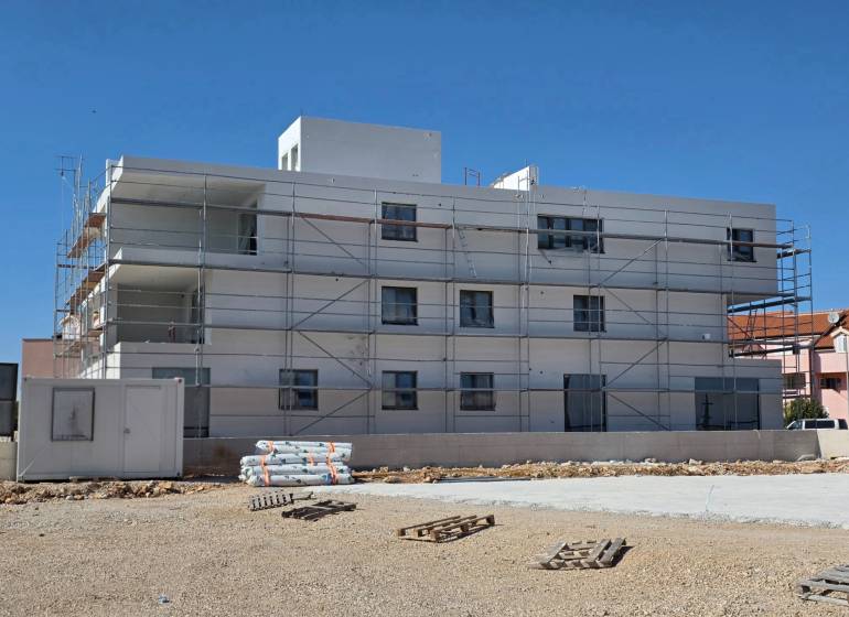 Budova ve městě SRIMA s lešením a nepořádkem na zemi.