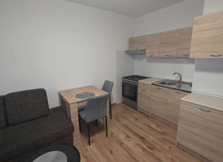 Kuchyně v 1-pokojovém bytě s dřevěným dekorem podlahy a nábytku.