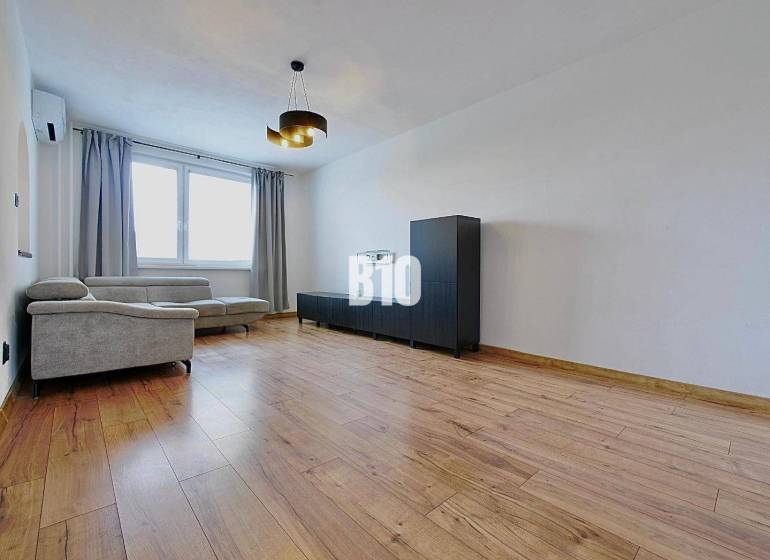 Obývací pokoj ve 3-pokojovém bytě s pohodlnou sedačkou a podlahou s dřevěným dekorem.