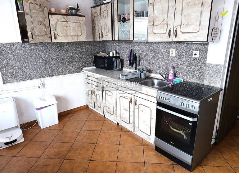 Kuchyně s dlažbou a kuchyňskou linkou v 2-pokojovém bytě.