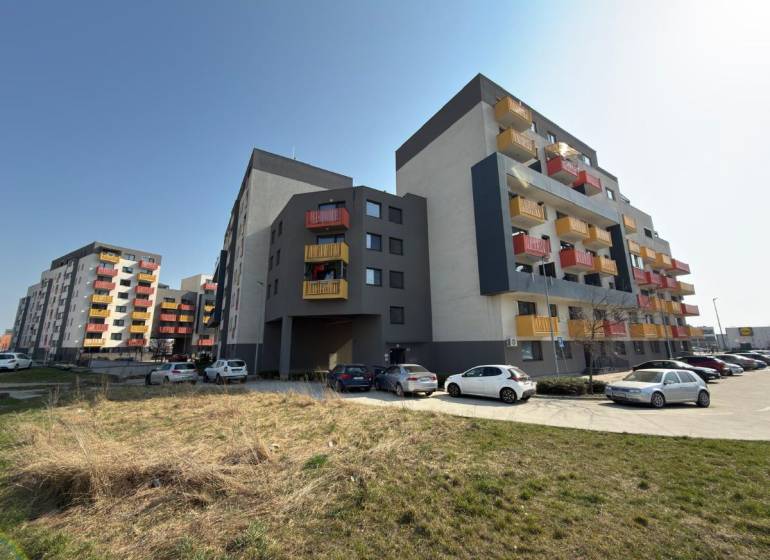 Bytové domy na Mikovíniho ulici v Trnavě s parkovištěm a zelenou plochou.