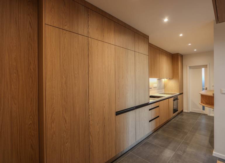 Kuchyně ve 3-pokojovém bytě s podlahou s dřevěným dekorem a vestavěnými spotřebiči.