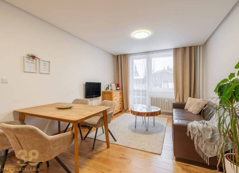 Obývací pokoj v rekreačním apartmánu s útulnou pohovkou a podlahou s dřevěným dekorem.