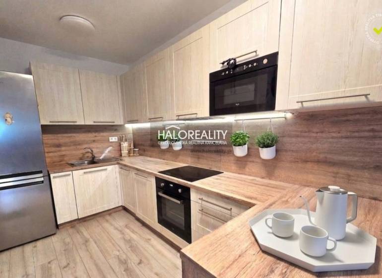 Moderní kuchyně v 2pokojovém bytě s dřevěným dekorem a vestavěnými spotřebiči.