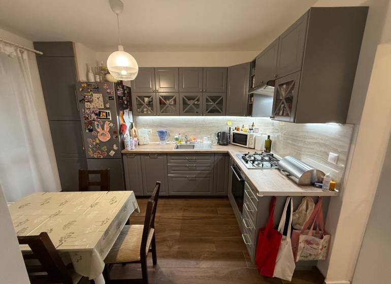 Kuchyně ve 4-pokojovém bytě s podlahou s dřevěným dekorem a rohovou kuchyňskou linkou.