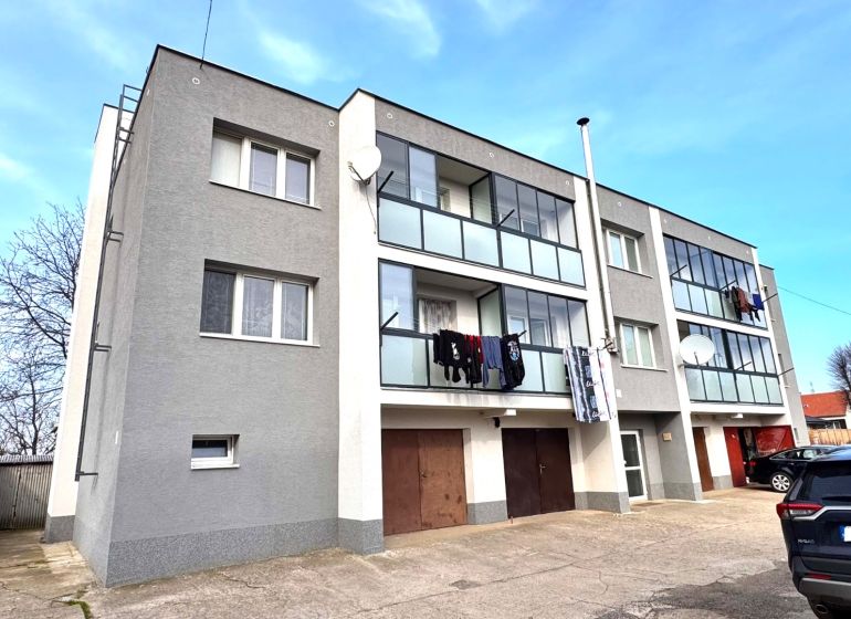 Třípatrový bytový dům s balkony a auty v Hlbokom.