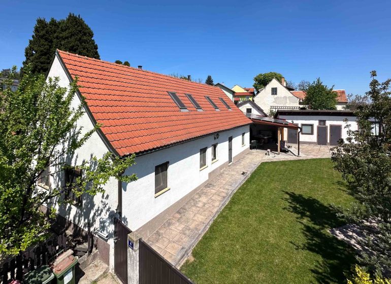 Rodinný dům ve městě Berg s červenou střechou a zeleným trávníkem.