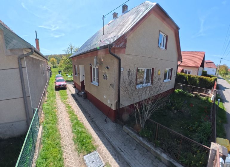 Rodinný dům ve Svinné s automobilem na příjezdové cestě a udržovanou zahradou.
