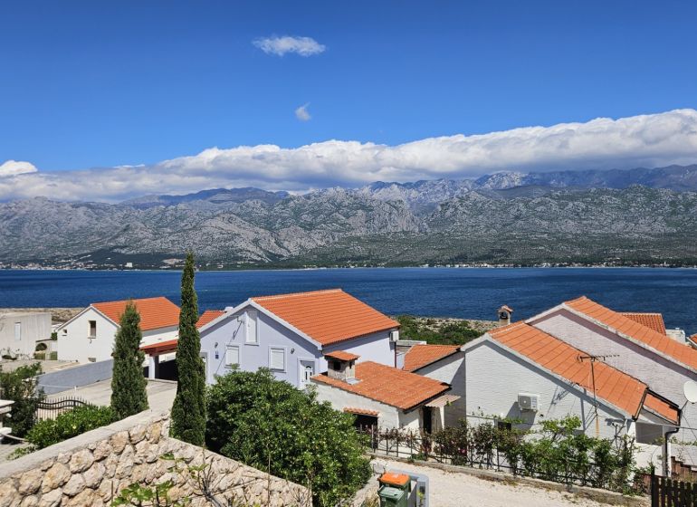 Rodinné domy ve Vinjeraci s výhledem na moře a horské panorámy.