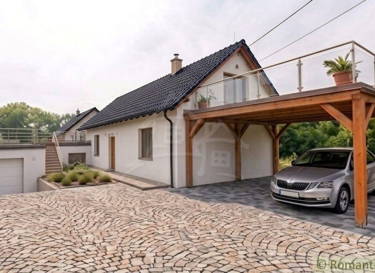 Rodinný dům v Sobotišti se šikmou střechou, terasou a dřevěným přístřeškem pro auto.