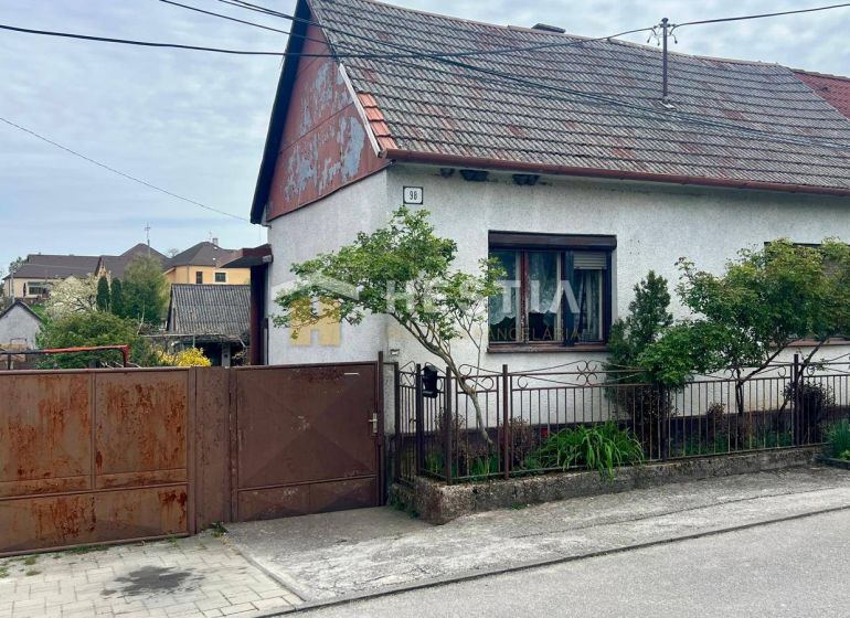 Rodinný dům v Cerové s bránou a malou zahradou, obklopený zelení.