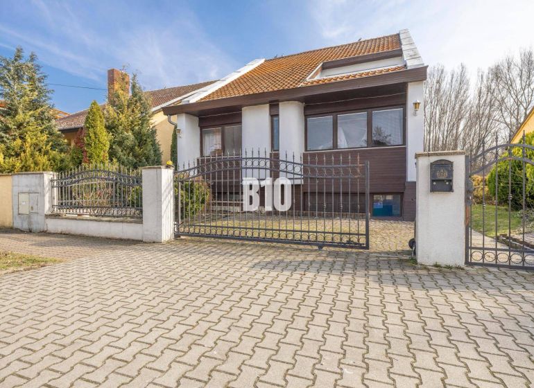 Rodinný dům na Dunajské ulici v Hamuliakovu s kovovou bránou a zahradou.