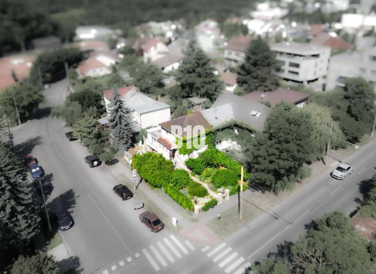 Rodinný dům v lokalitě Bratislava - Staré Město, obklopený zelení a cestou s auty.
