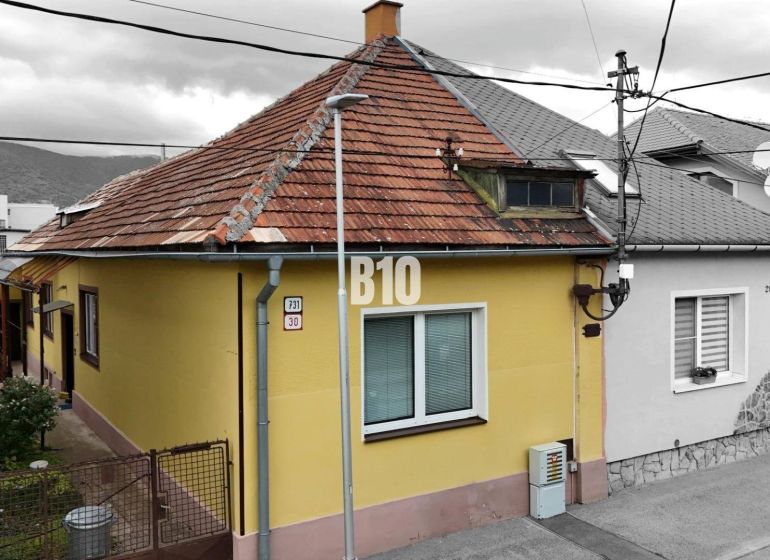 Rodinný dům v Martině se žlutou fasádou a šikmou střechou, vedle přístupového chodníku.