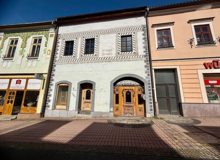 Ulice Dolná v Banské Bystrici zobrazuje historické budovy s obchody a barem.