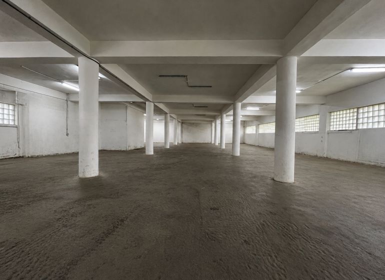 Prostorný interiér s betonovou podlahou a bílými sloupy ve skladech a halách.