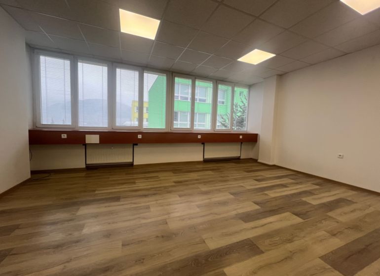 Prázdná kancelář s podlahou s dřevěným dekorem a velkými okny.