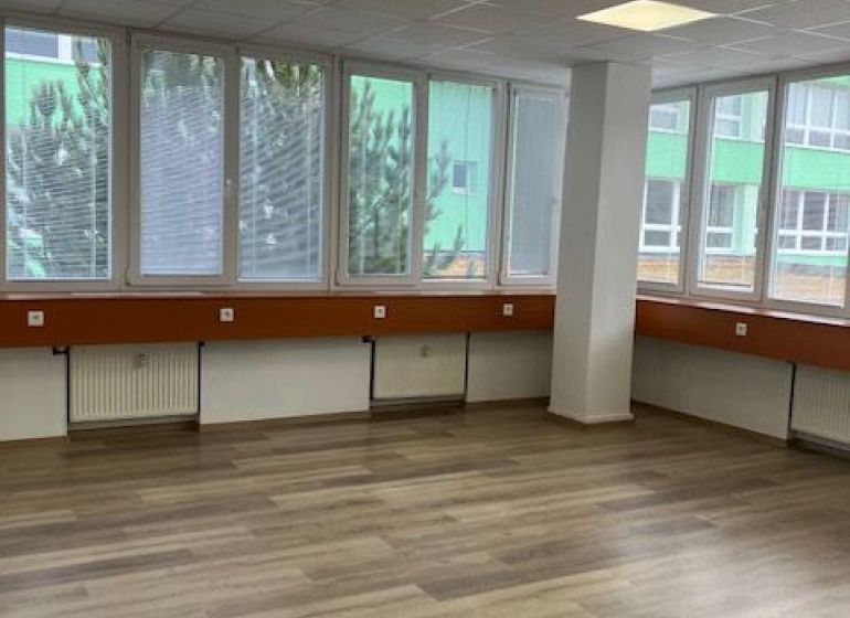 Kanceláře s podlahou s dřevěným dekorem a velkými okny.