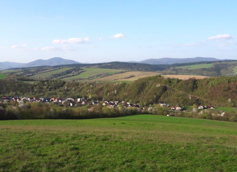 Pohled na zemědělské a lesní pozemky v Bogliarce s kopcovitým horizontem a vesnicí.