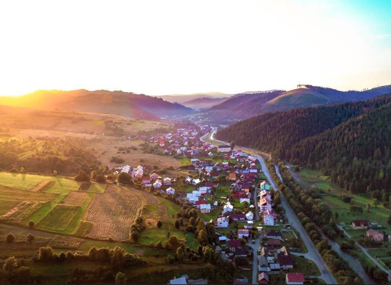 Krajina v okolí Nové Bystrice se zemědělskými a lesními pozemky při západu slunce.