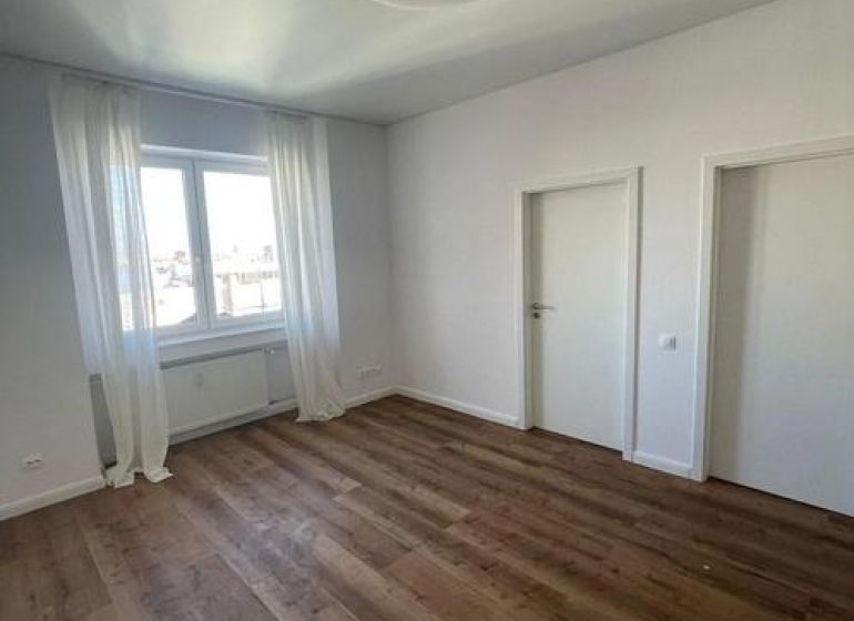 Pokoj s podlahou s dřevěným dekorem, bílými stěnami a závěsy v 3-pokojovém bytě.