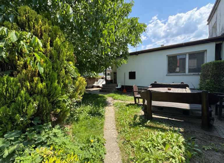 Zahrada rodinného domu v Bratislavě - Ružinově na Sennej ulici s dřevěným posezením.