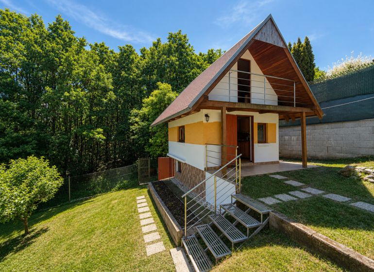 Chata s dřevěným dekorem v Považské Bystrici na Klučině, obklopená zelení a stromy.