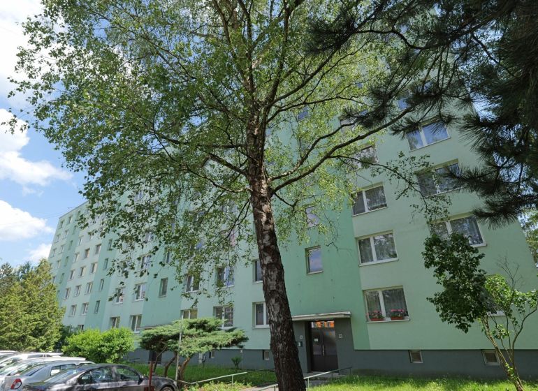Považská Bystrica, Štúrova: Panelový dům obklopený stromy a zaparkovanými auty na ulici.