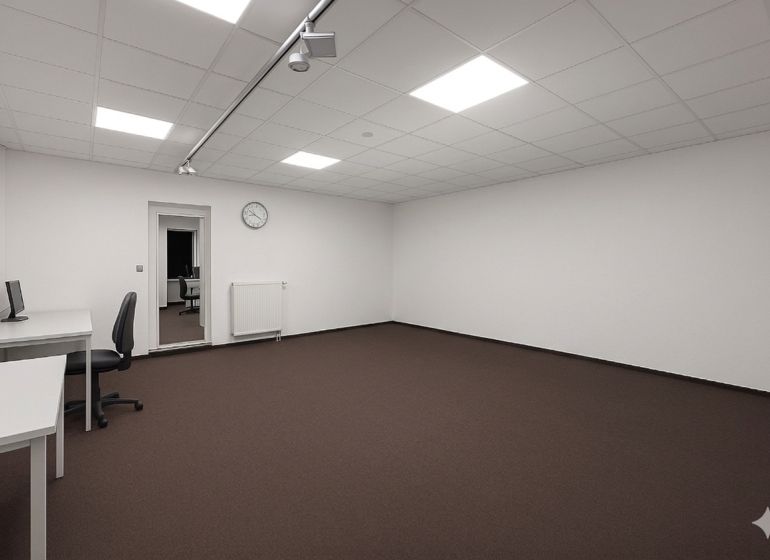 Priestranné kanceláře s bílými stěnami, hnědým kobercem a minimalistickým zařízením.