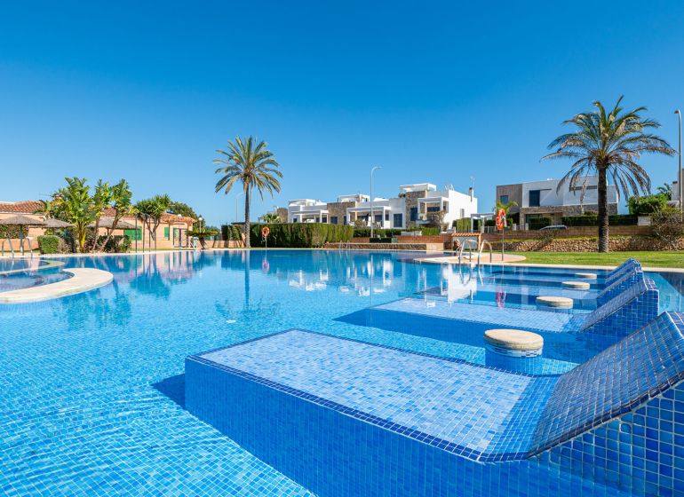 Bazén u rekreačního apartmánu v Cala Murada na Mallorce s palmami a lehátky.