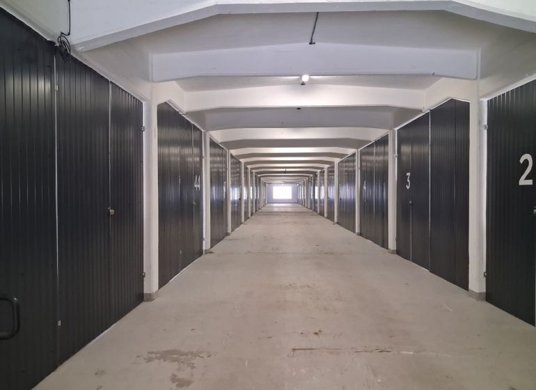 Dlouhá chodba s garážovými boxy ve skladech a halách.
