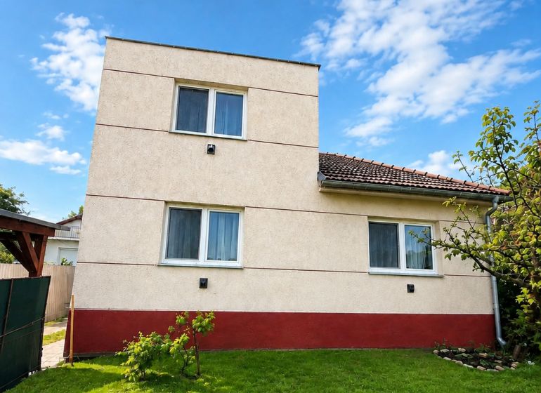 Rodinný dům v Šalgovcích s udržovaným trávníkem pod modrou oblohou.
