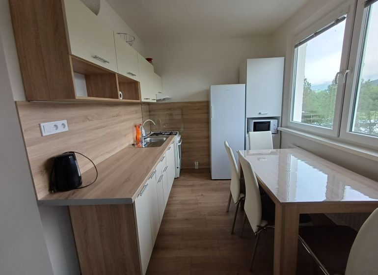Kuchyně v 3-pokojovém bytě s podlahou s dřevěným dekorem a moderním zařízením.