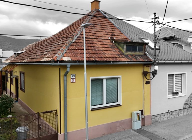 Rodinný dům v Martině se šikmou střechou a žlutou fasádou.