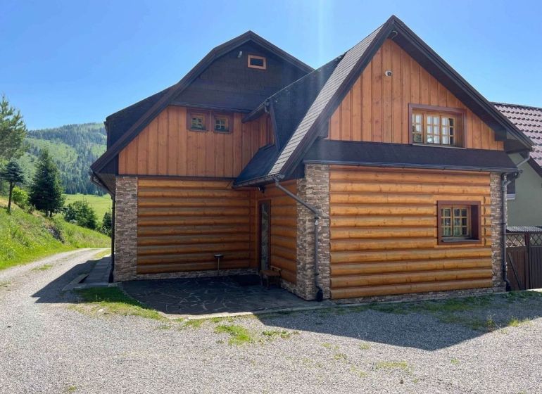 Rodinný dům ve Velkém Borovém s dřevem a kamenem obloženým exteriérem u lesa.