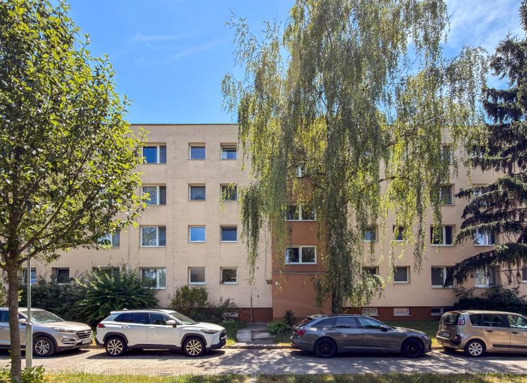 Bytový dům na ulici Staré zahrady v Bratislavě - Ružinově obklopený zelení a auty.