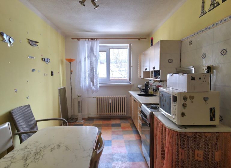 Kuchyně v 2-pokojovém bytě se žlutými stěnami a kostkovanou podlahou.