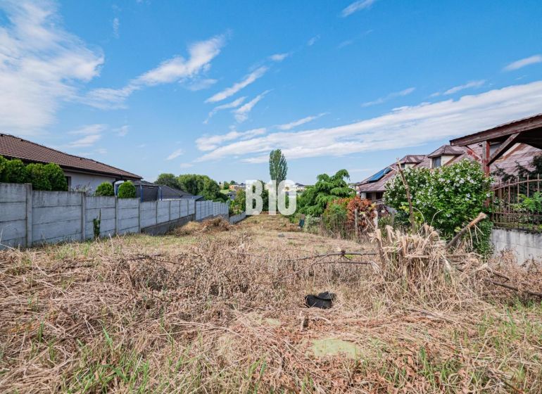 Pozemky - bydlení v Nitře, ohraničené plotem, s výhledem na modrou oblohu.