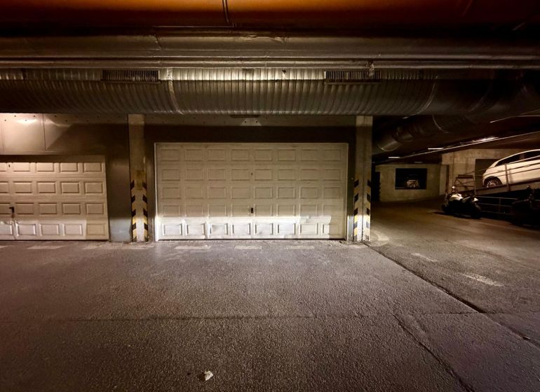 Interiér garáží s uzavřenými vraty a zaparkovanými vozidly.