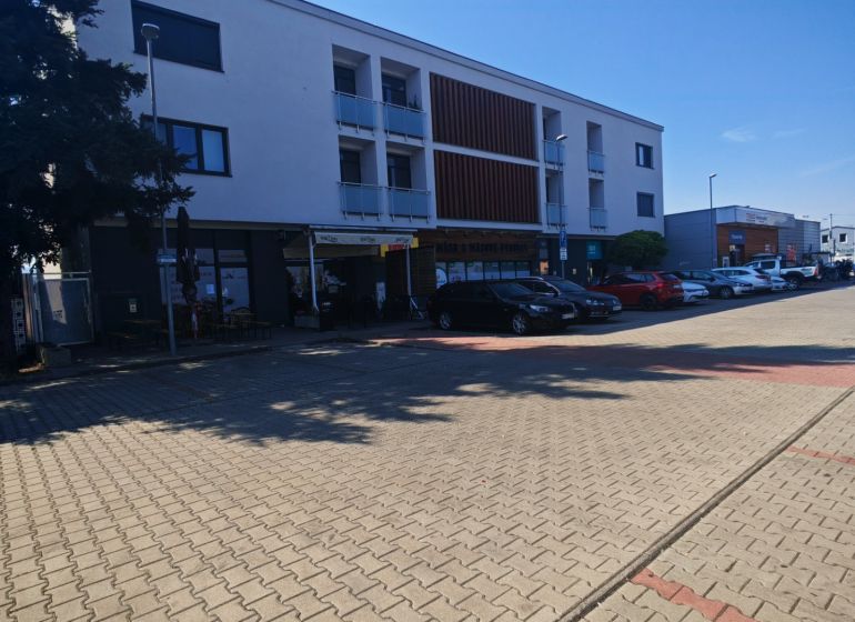 Budova na Senické ulici v Rohožníku s parkovacími místy v popředí.