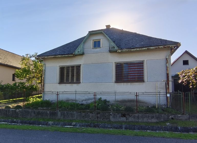 Rodinný dům na Komenského ulici v Čebovcích s mírně zanedbanou fasádou a zahradou.