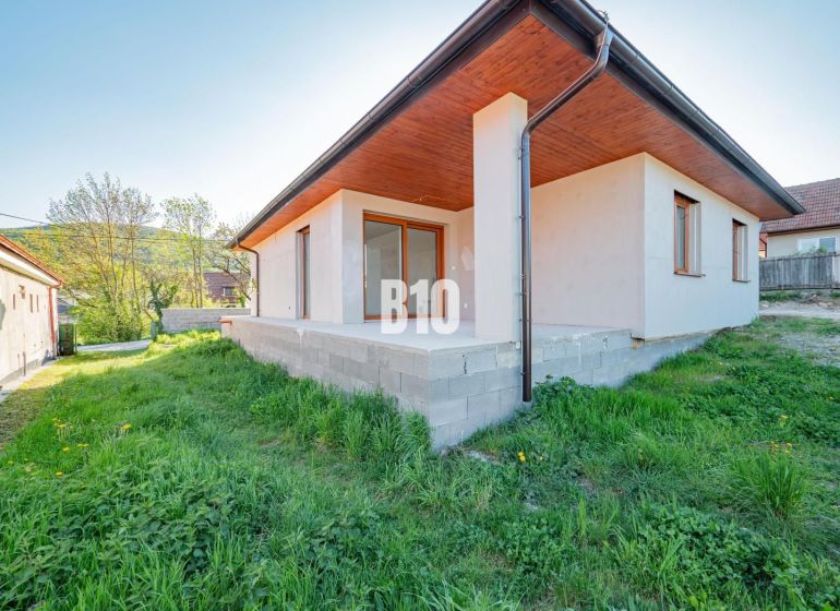 Rodinný dům v Nitře s betonovou terasou a zeleným trávníkem v zahradě.