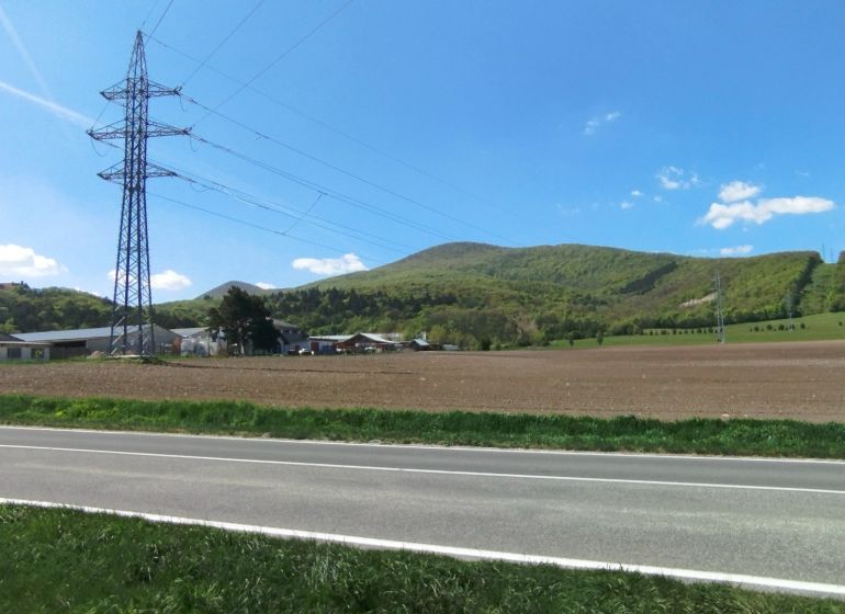 Krajina na Továrenské v Smolenicích se zemědělskými a lesními pozemky a elektrickým vedením.