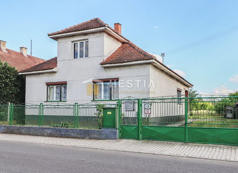 Rodinný dům v Borském Mikuláši s bílými stěnami a zeleným plotem.