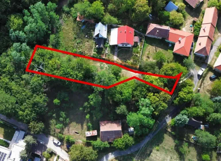 Letecký pohled na parcelu v zahradách Kolačna, obklopenou zelení a nemovitostmi.