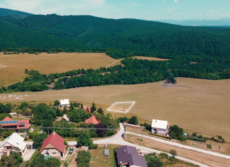 Venkovský pohled na pozemky k bydlení v Podhradí obklopené lesy a loukami.