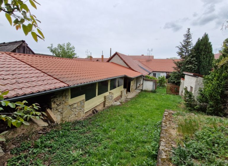 Zahrada u rodinného domu v Mokrém Háji s kamennou zdí a červenou střešní krytinou.