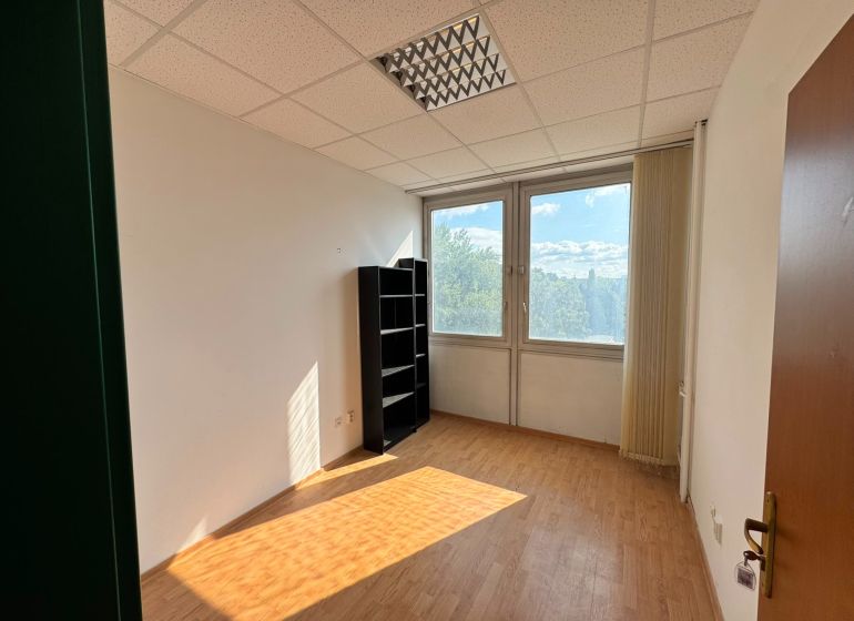 Kanceláře s podlahou s dřevěným dekorem a okny s výhledem na zeleň.